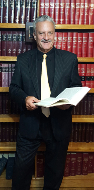 Neil L. Calanca standing next to a book case.